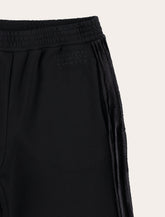 MM6 Maison Margiela Kids black jogger trousers with side bands -  | Spazio Pritelli